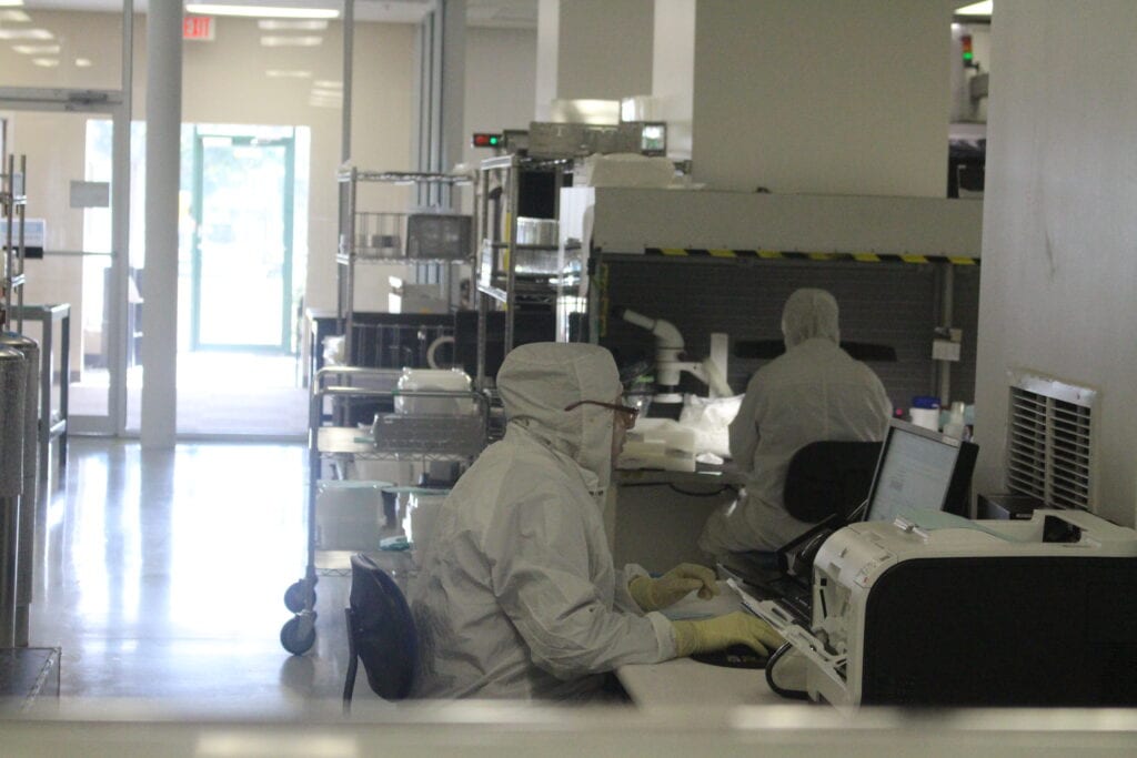 Two people in protective suits working in laboratory